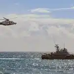 Opération de sauvetage en mer avec embarcation et migrants arrivant à la côte