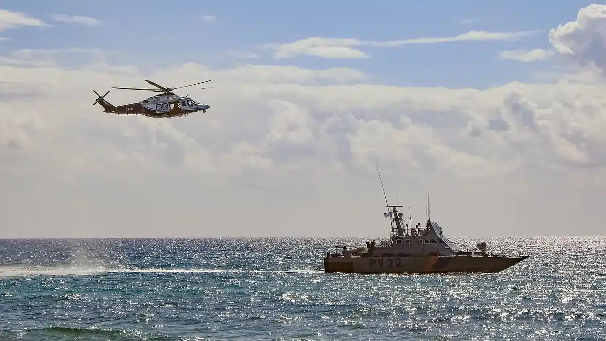 Opération de sauvetage en mer avec embarcation et migrants arrivant à la côte