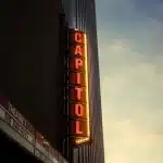 Affichage d'une salle de cinéma avec plusieurs titres de films et dates de sortie sous des lumières colorées