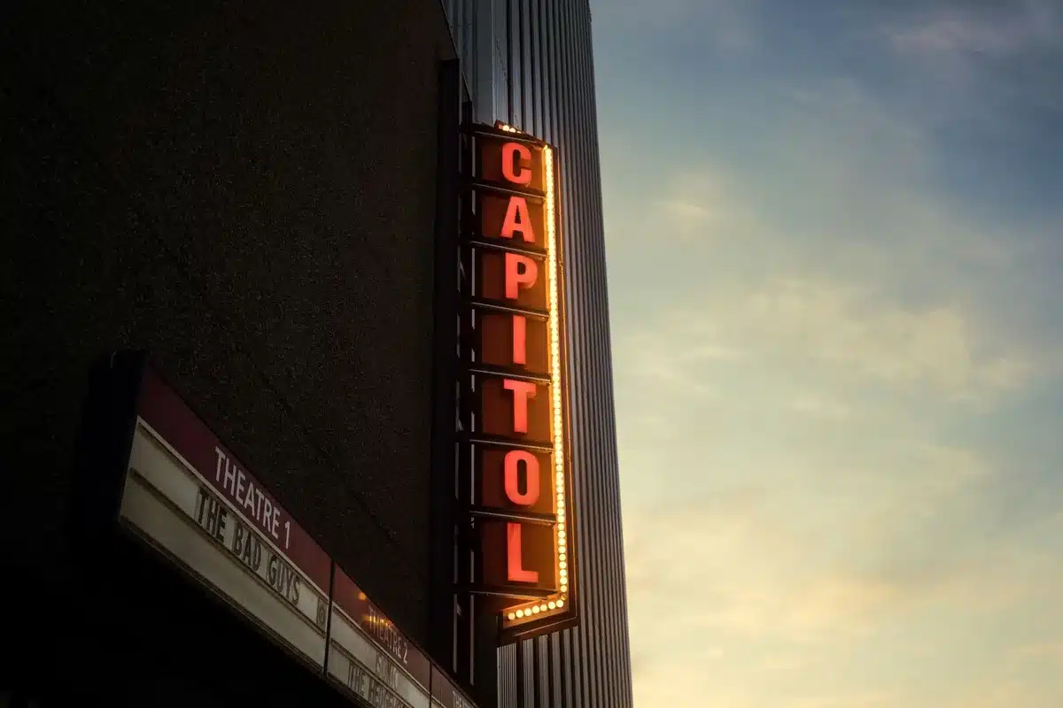 Affichage d'une salle de cinéma avec plusieurs titres de films et dates de sortie sous des lumières colorées