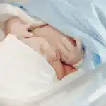 Main d'un nouveau-né enserrant le doigt d'un parent dans une maternité