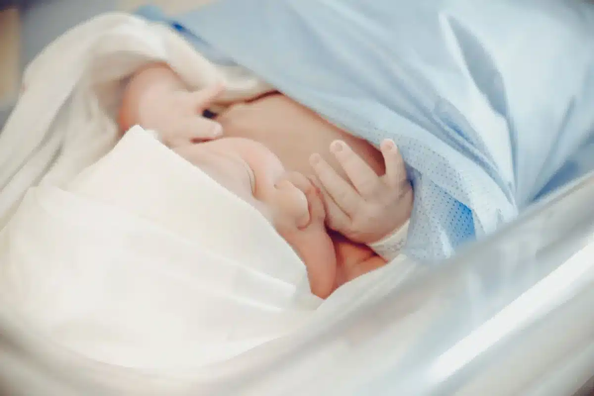Main d'un nouveau-né enserrant le doigt d'un parent dans une maternité