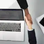 Deux personnes se serrent la main au-dessus de documents commerciaux dans un bureau moderne