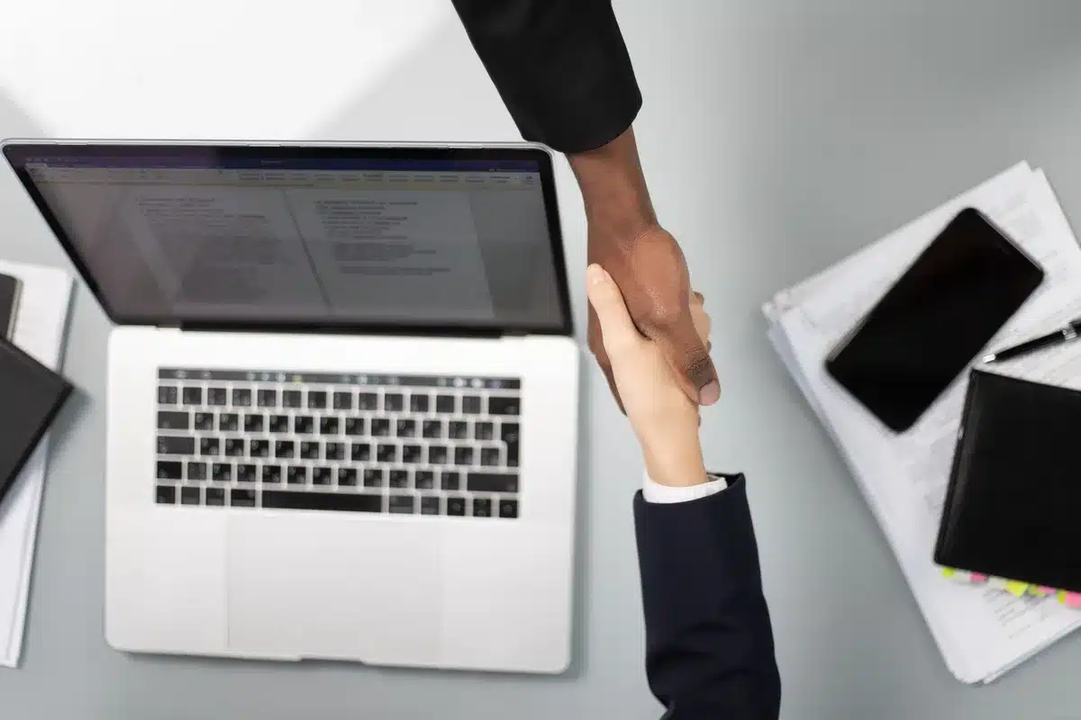 Deux personnes se serrent la main au-dessus de documents commerciaux dans un bureau moderne