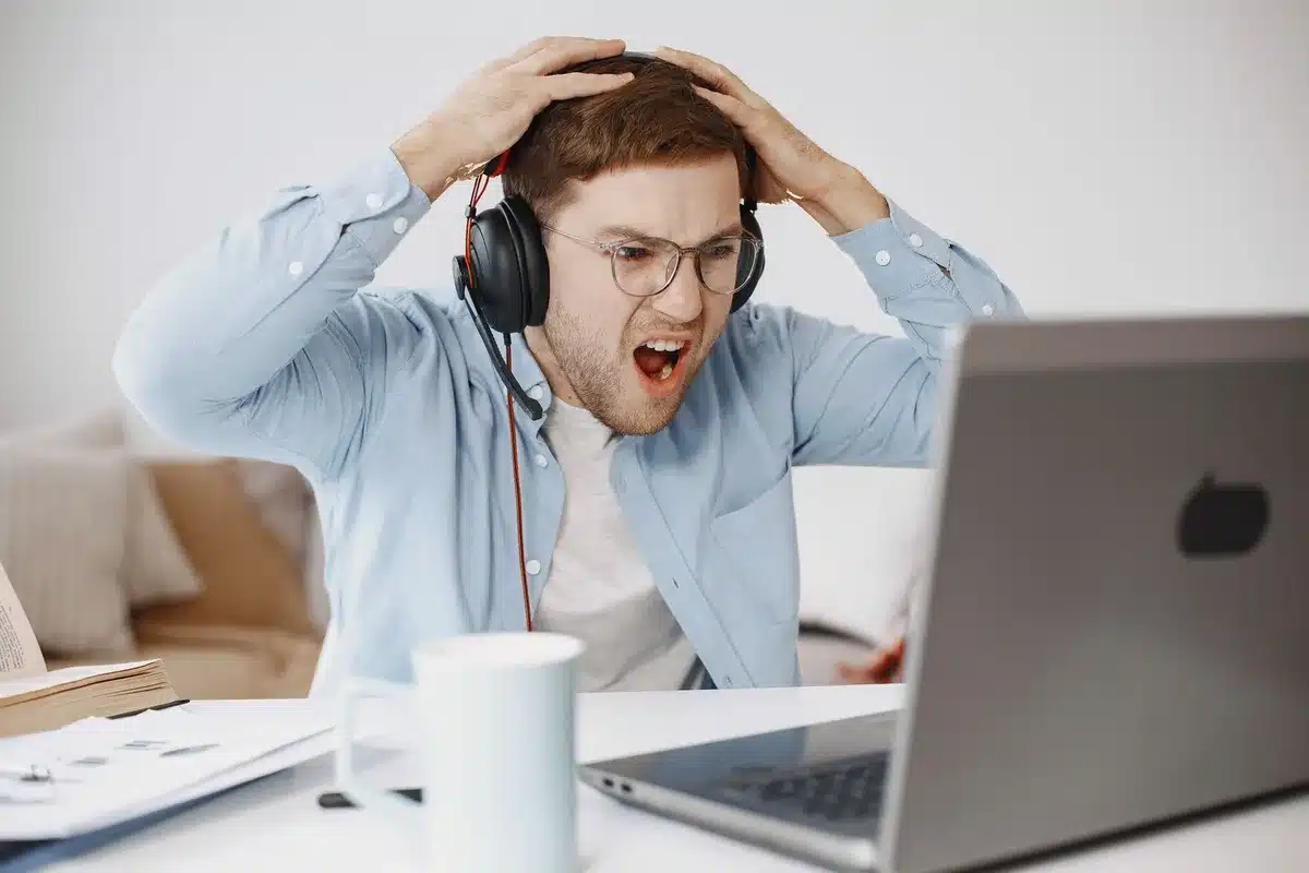 Jeune professionnel travaillant à distance, face concentrée montrant les défis d'intégration en télétravail