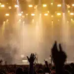 Un artiste sur scène sous les projecteurs face à un public enthousiaste lors d'un concert