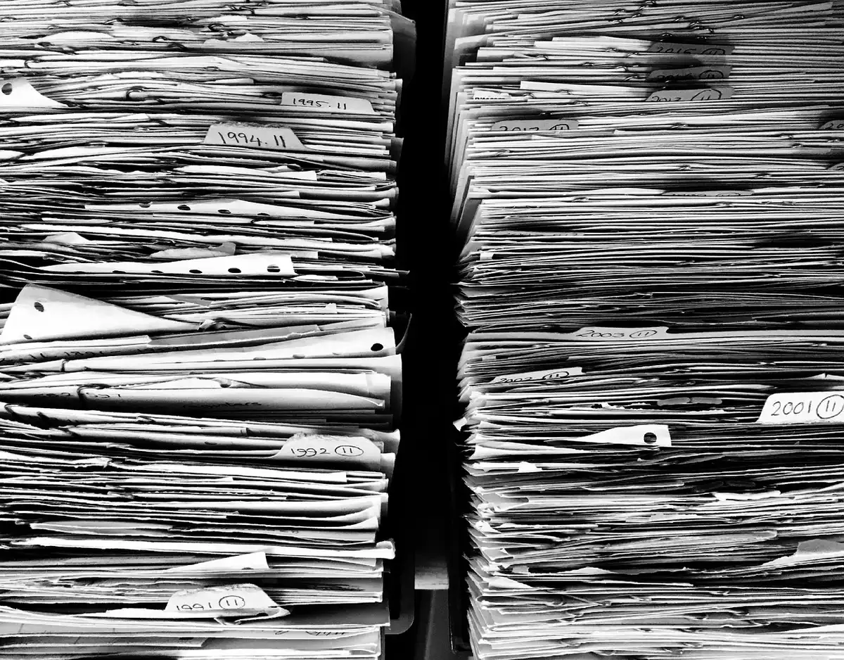 Chercheur feuilletant des archives anciennes derrière une vitre