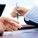 Mains anonymes tendant un document financier dans une salle de réunion