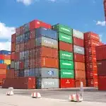 Quai de marchandises avec containers et palettes, silhouettes anonymes