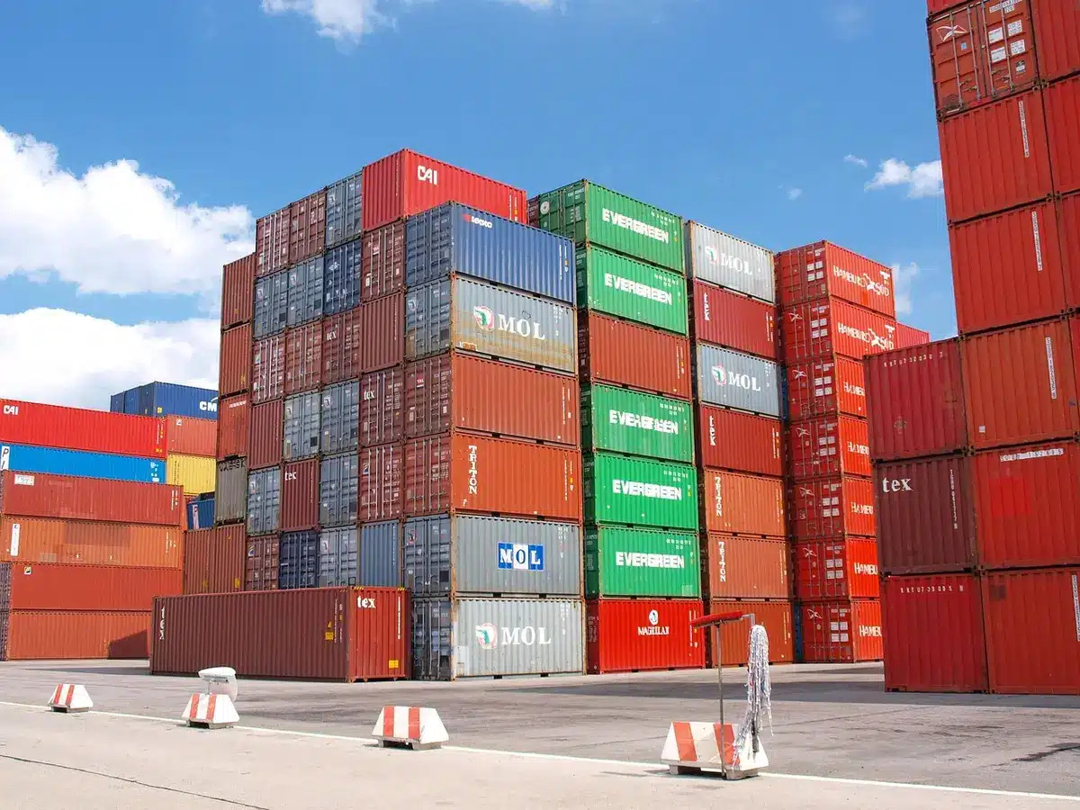 Quai de marchandises avec containers et palettes, silhouettes anonymes
